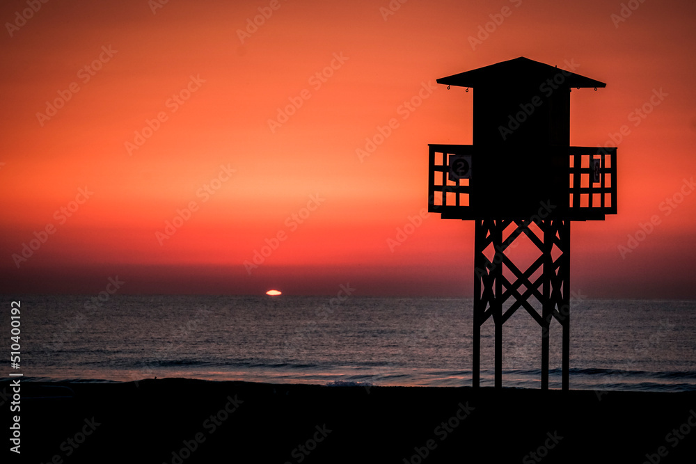 Red sunset on the beach with a lifeguard watchtower