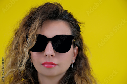 Close-up portrait of a beautiful girl on a yellow background. a woman in black glasses looks thoughtfully. human emotions