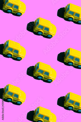 pattern of a yellow toy car on a pink background. minimal aesthetic.