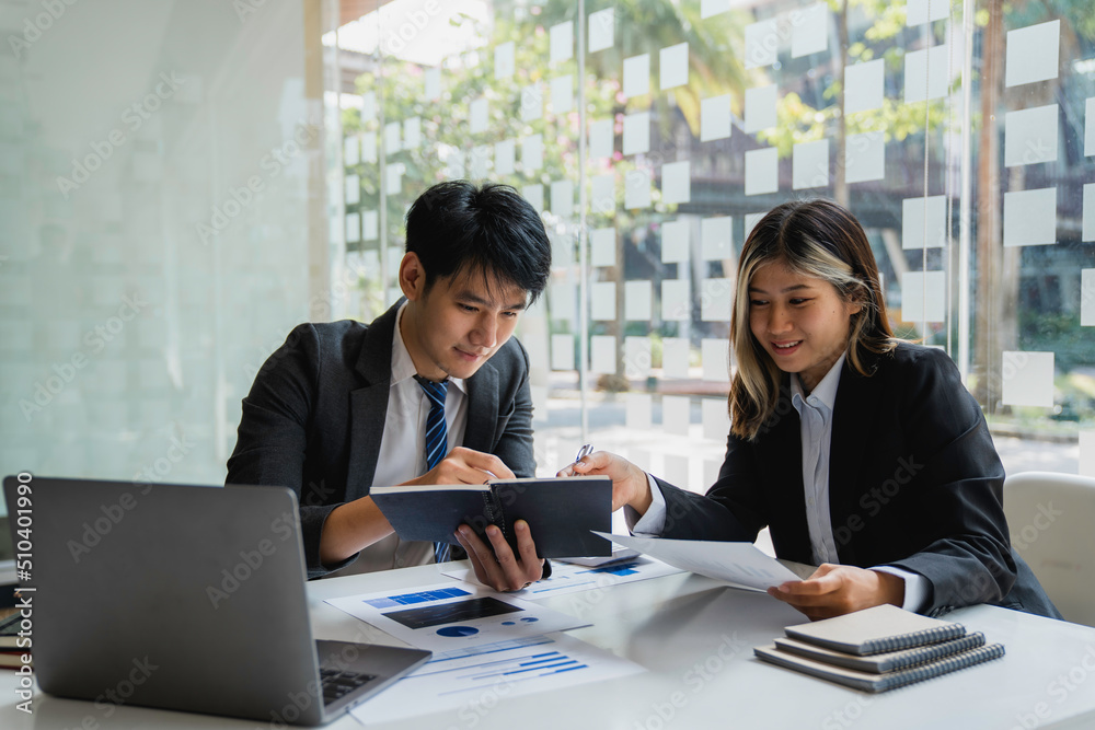 Team of Asian young business people analyzing data using a computer while talking about marketing strategy and planning working in the office