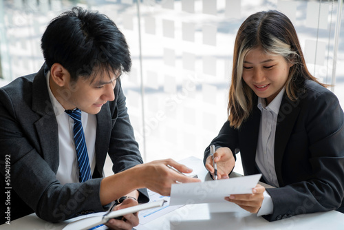 Team of Asian young business people analyzing data using a computer while talking about marketing strategy and planning working in the office