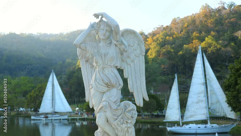 Antique stone female statue in sunset sunlight with yacht sail boats on