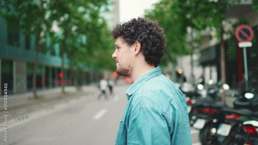 Close-up of young bearded man in denim shirt smiling crossing the road at crosswalk on modern city background Close-up of young bearded man in denim shirt smiling crossing the road at crosswalk on modern city background