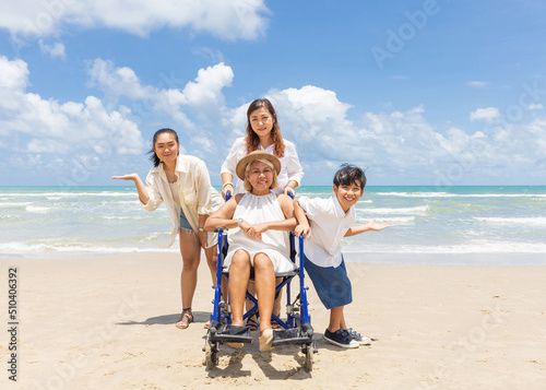 senior woman in a wheelchair with family enjoy travel on the beach