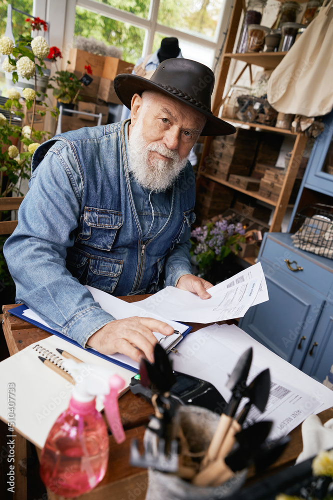 Senior man cheking accoungs in own flower shop Senior man cheking accoungs in own flower shop