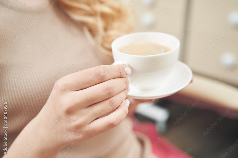 Female is keeping cup of coffee in hands Female is keeping cup of coffee in hands