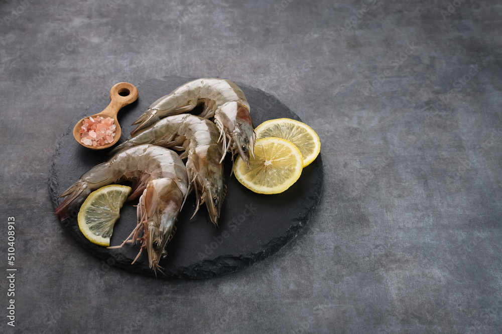 Fresh shrimps served on plate board with dark background. Food preparation
Fresh shrimps served on plate board with dark background. Food preparation