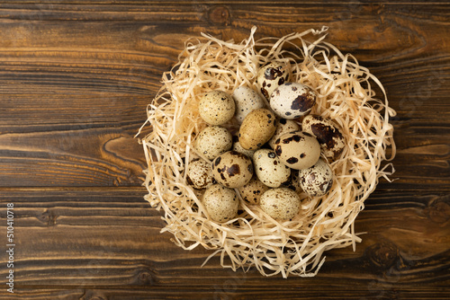 Quail eggs in a nest on a brown texture background.Organic food. Place for text. fresh eggs
