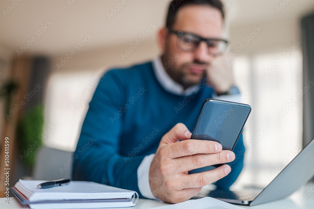 Close-up of bored male professional using smart phone at office desk Close-up of bored male professional using smart phone at office desk
