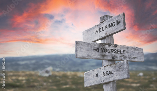 Foto helping yourself heal text quote caption on wooden signpost outdoors in nature with dramatic sunset skies