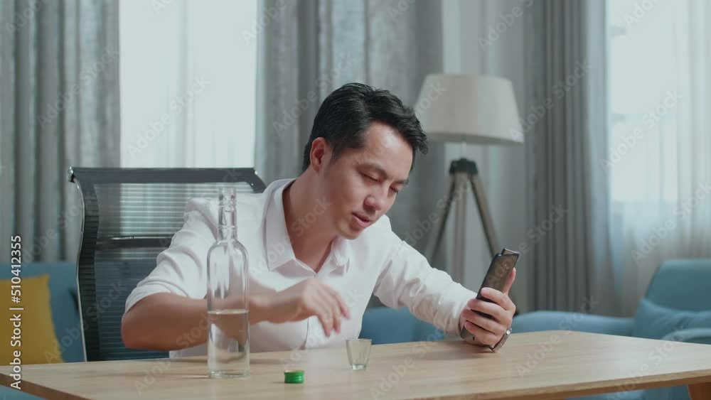 Asian Man Pouring Vodka In A Shot Glass Before Cheering And Drinking During Having Video Call On Smartphone At Home
Asian Man Pouring Vodka In A Shot Glass Before Cheering And Drinking During Having Video Call On Smartphone At Home