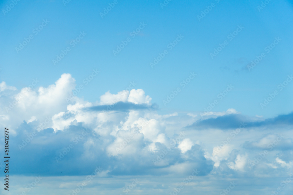 Heavy cumulus clouds in the blue sky. White-blue clouds background. Copy space from above.