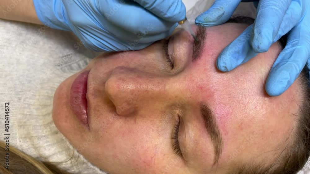 Eyebrow permanent make-up. Close-up of a woman with thick eyebrows in a beauty salon. Beautician makes eyebrow tattoo for a woman's face. beauty procedure. Eyebrow permanent make-up. Close-up of a woman with thick eyebrows in a beauty salon. Beautician makes eyebrow tattoo for a woman's face. beauty procedure.