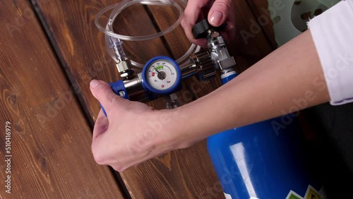 A nurse opens the oxygen supply in a medical oxygen cylinder in close-up. Hospital equipment concept