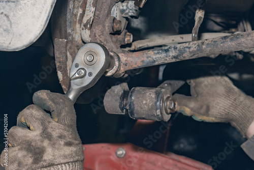 Mechanic repairs the running gear of a car car. Hands of a mechanic close-up. Small business concept.