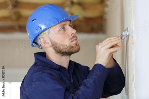 construction worker with long trowel plastering a wall