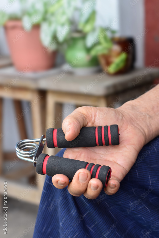 Asian, Myanmar old man gripping hand exercise gripper.