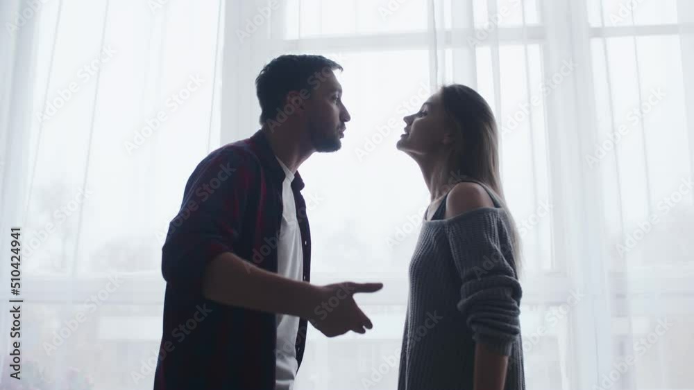 Stressed young married family couple arguing emotionally, blaming lecturing each other, sitting on couch. Depressed husband quarreling with wife, having serious relations communication problems. Stressed young married family couple arguing emotionally, blaming lecturing each other, sitting on couch. Depressed husband quarreling with wife, having serious relations communication problems.