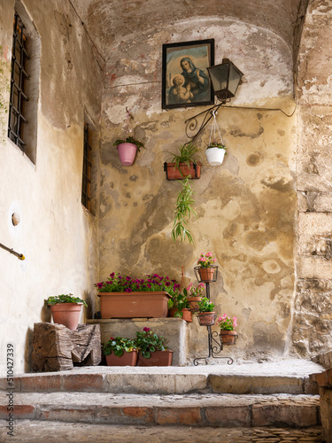 Amelia (Italy) Medieval alley, with flowers and image of the Virgin and Child, illuminated by a lamppost 