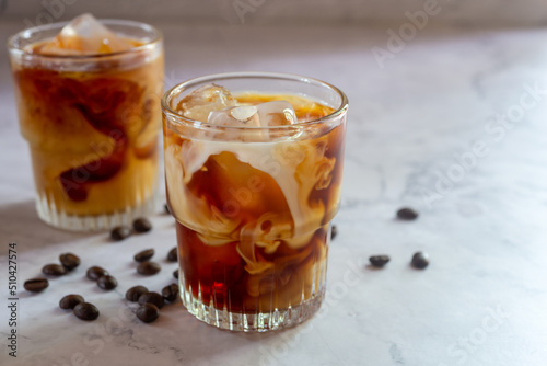 glasses of homemade cold brew coffee with milk on white table background.