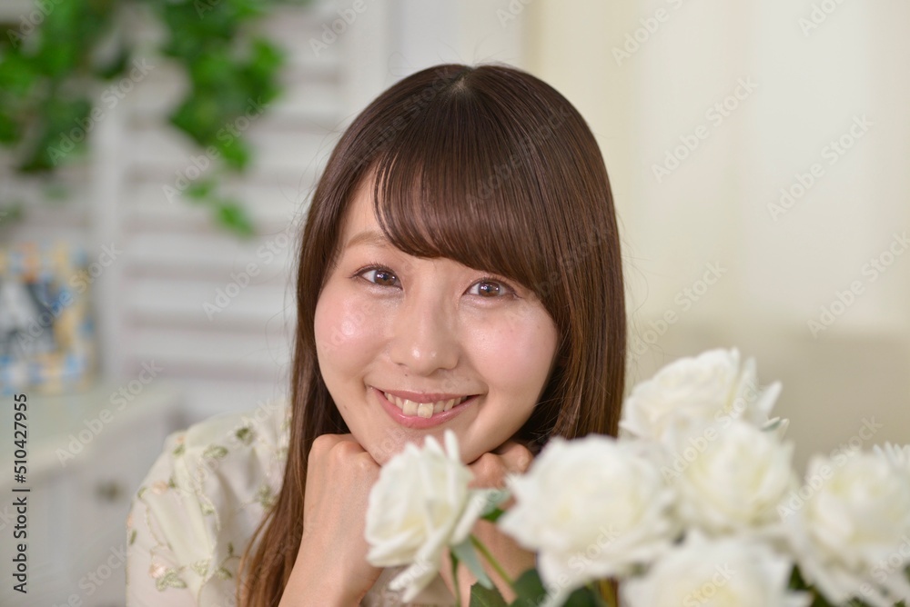 室内にて頬杖をついて微笑む可愛らしい日本人女性の表情	
