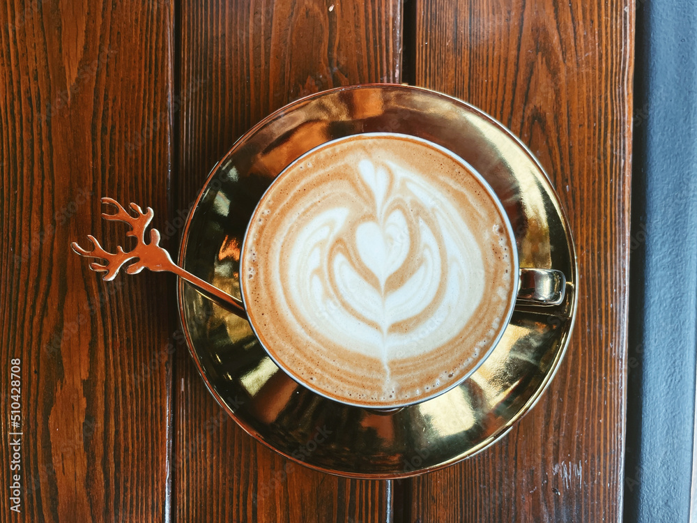 Top view of cappuccino in epic golden cup on wooden table. Top view of cappuccino in epic golden cup on wooden table.