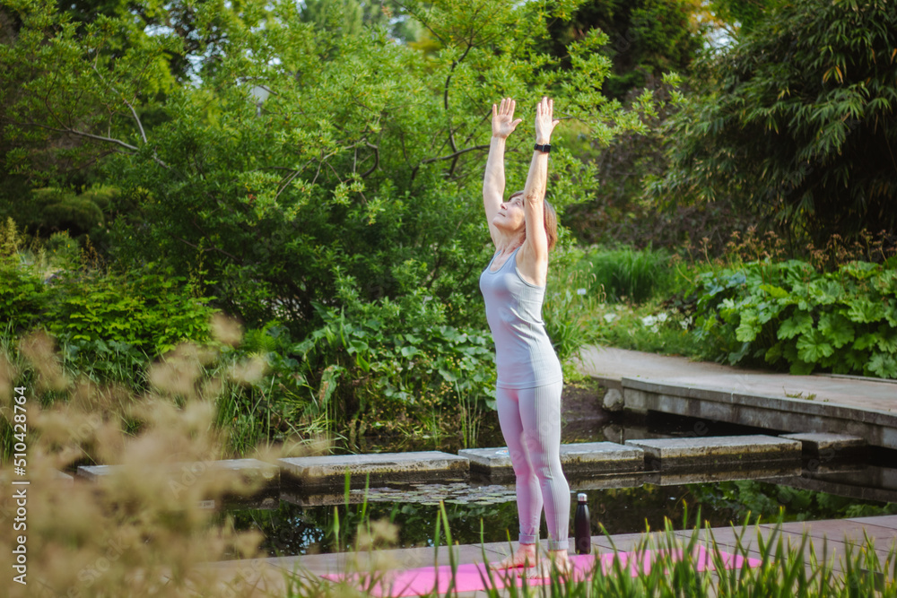 An old slender woman does yoga in the park