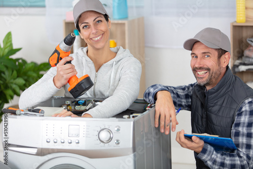 male and female repairers stanging near washing machine photo