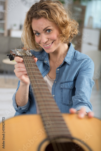 woman holding an acoustic guitar to check it