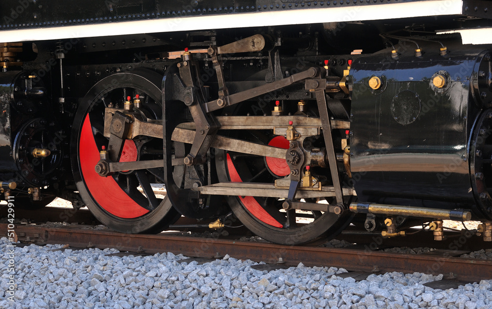 Mecanismo de braços e rodas de uma locomotiva a vapor parada em cima de carris