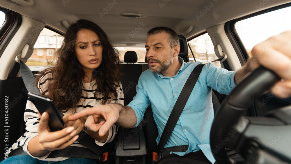Confused Couple Riding Auto, Driving And Using Mobile Application, Panorama Confused Couple Riding Auto, Driving And Using Mobile Application, Panorama