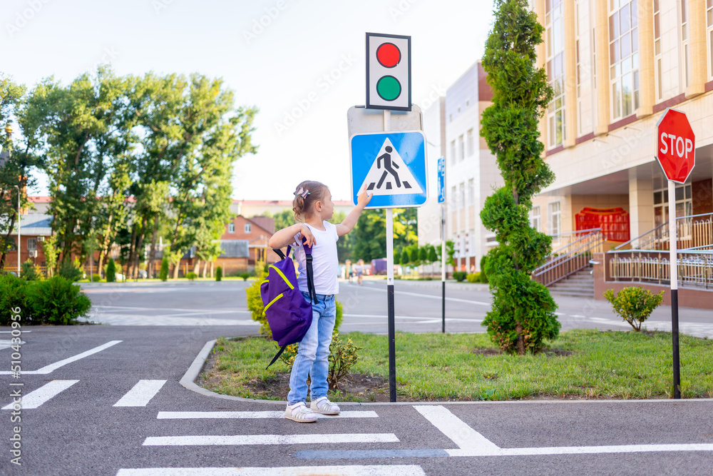 a schoolgirl girl crosses the road on a zebra near the road sign pedestrian crossing going to school with a backpack the concept of traffic rules a schoolgirl girl crosses the road on a zebra near the road sign pedestrian crossing going to school with a backpack the concept of traffic rules