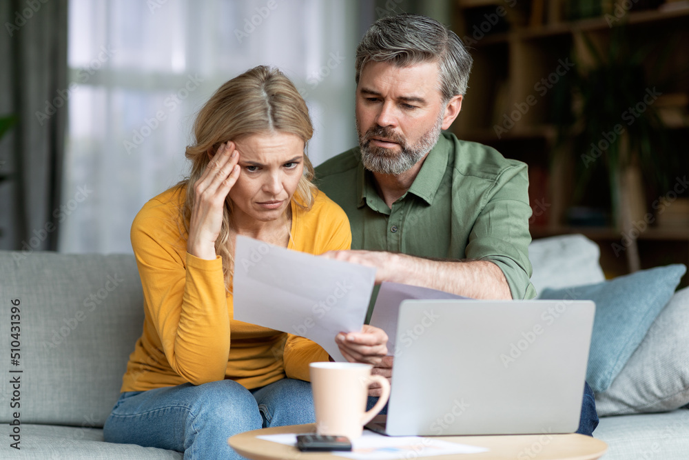 Stressed Middle Aged Spouses Checking Financial Papers At Home