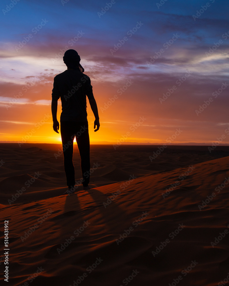 silhouette of a man walking in the desert at sunset