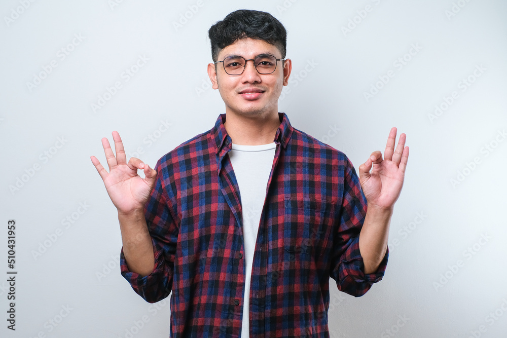 Handsome young man smiling positive doing ok sign with hand and fingers. successful expression. Handsome young man smiling positive doing ok sign with hand and fingers. successful expression.