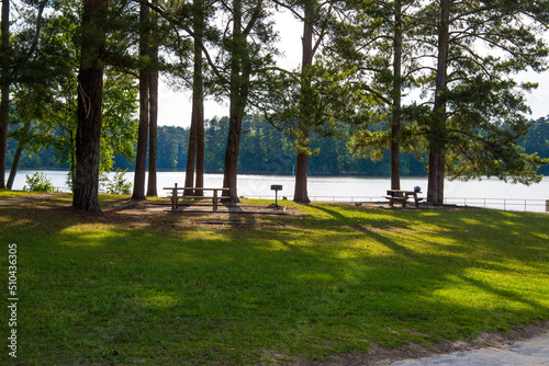 a gorgeous summer landscape at Lake Acworth with blue lake water and park benches and barbeque pits  surrounded by lush green trees, grass and plants at Proctor Landing Park in Acworth Georgia USA photo