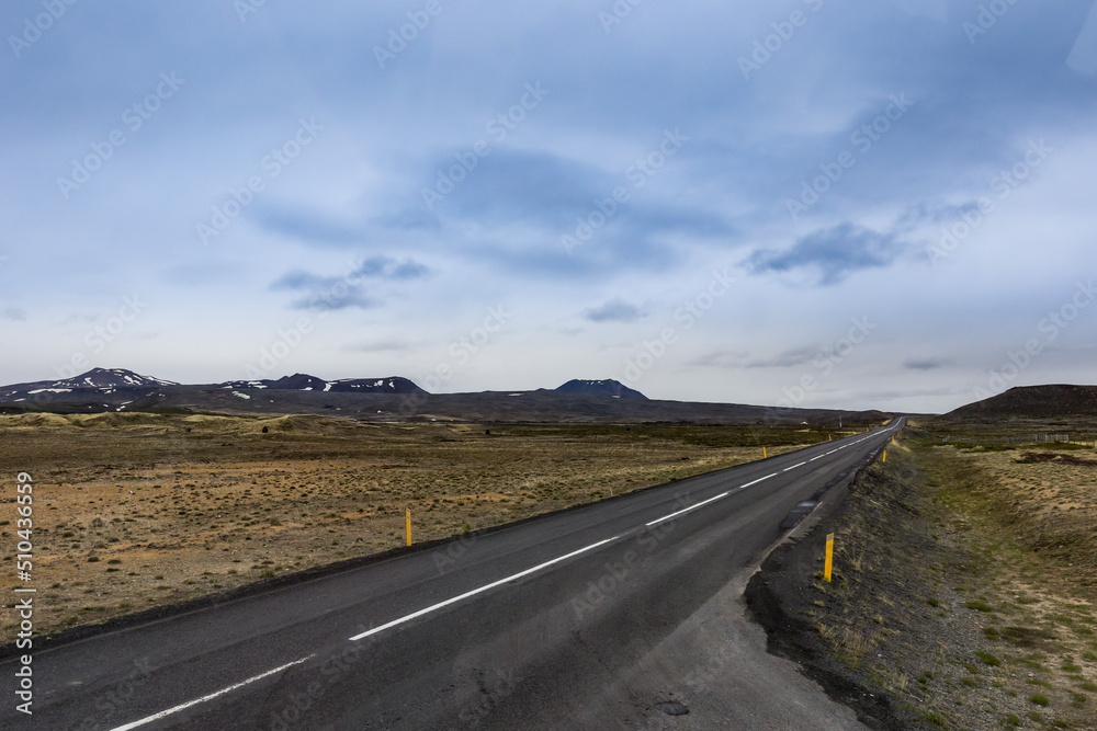 A road through no vegetation but only moss covered fields of Northern Iceland