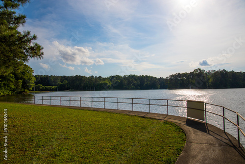 the gorgeous blue rippling waters of Lake Acworth with a long winding footpath around the lake surrounded by a metal rail and lush green trees, grass and plants at Proctor Landing Park in Acworth photo