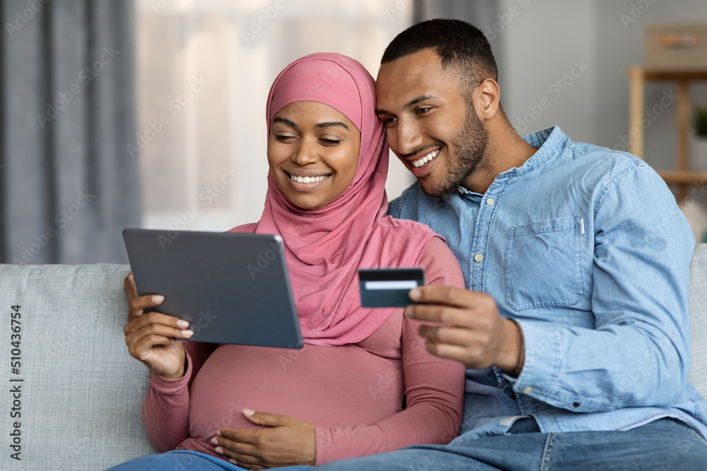 Black Muslim Pregnant Couple With Digital Tablet And Credit Card Shopping Online Black Muslim Pregnant Couple With Digital Tablet And Credit Card Shopping Online