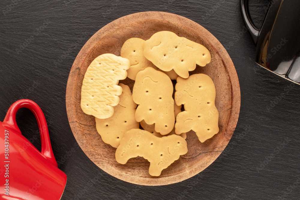 Several homemade zoological cookies with a wooden saucer and two cups on a slate stone, close-up, top view. Several homemade zoological cookies with a wooden saucer and two cups on a slate stone, close-up, top view.