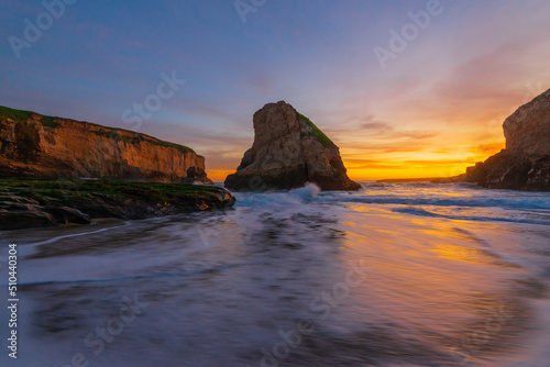 Sunset behind rocks with waves crashing on Santa Cruz beach