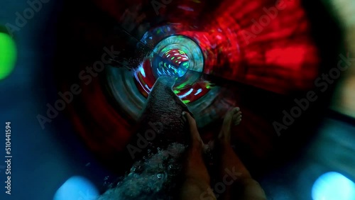 Teenager boy have fun in a closed slider at water Park. Fun on water. Enjoying water slider ride. Rider POV. Point of view in aqua park tube slide. Summer time. Multicolors view