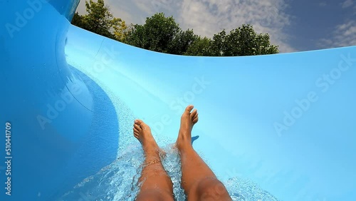 Teenager boy have fun in a closed slider at water Park. Fun on water. Enjoying water slider ride. Rider POV. Point of view in aqua park tube slide. Summer time. Multicolors view