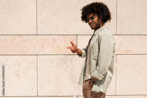 Outgoing Black man outdoor. African American man in casual clothes and sunglasses walking on sunny day. Portrait, city life concept