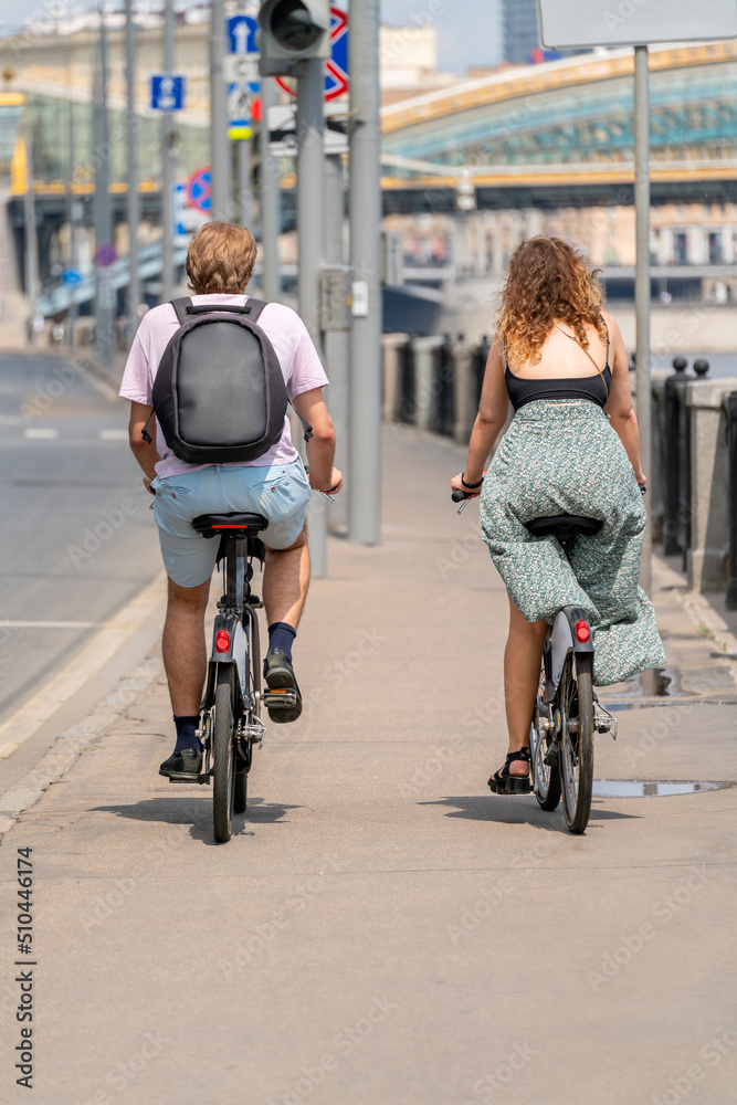 A young man and a girl are riding bicycles. Cyclists on the city street.