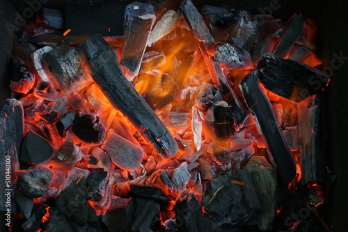 Charcoal is smoldering in the grill for cooking. Ashes, heat, smoke and fire of coals. Burning background