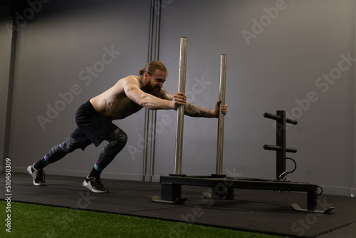 Tattoo adult athlete beard sleigh push athletic attractive body brunette, from drag equipment in healthy for heavy muscle, physical prowler. Strong women workout,