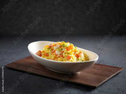 Supreme Seafood Fried Rice served in a dish isolated on cutting board side view on dark background