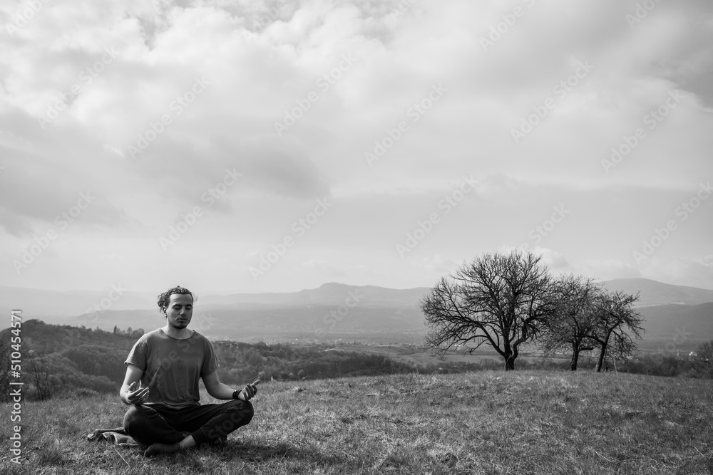 Young man do yoga on the mountain peak