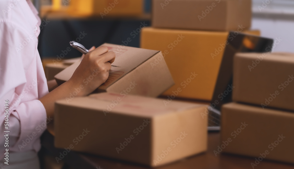 selling products online. A young woman is packing products to send to customers online. selling products online. A young woman is packing products to send to customers online.